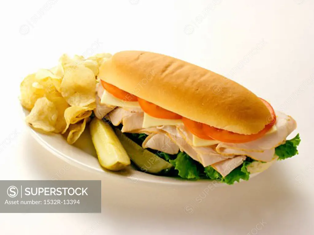 A Turkey Sub with Chips and Pickles