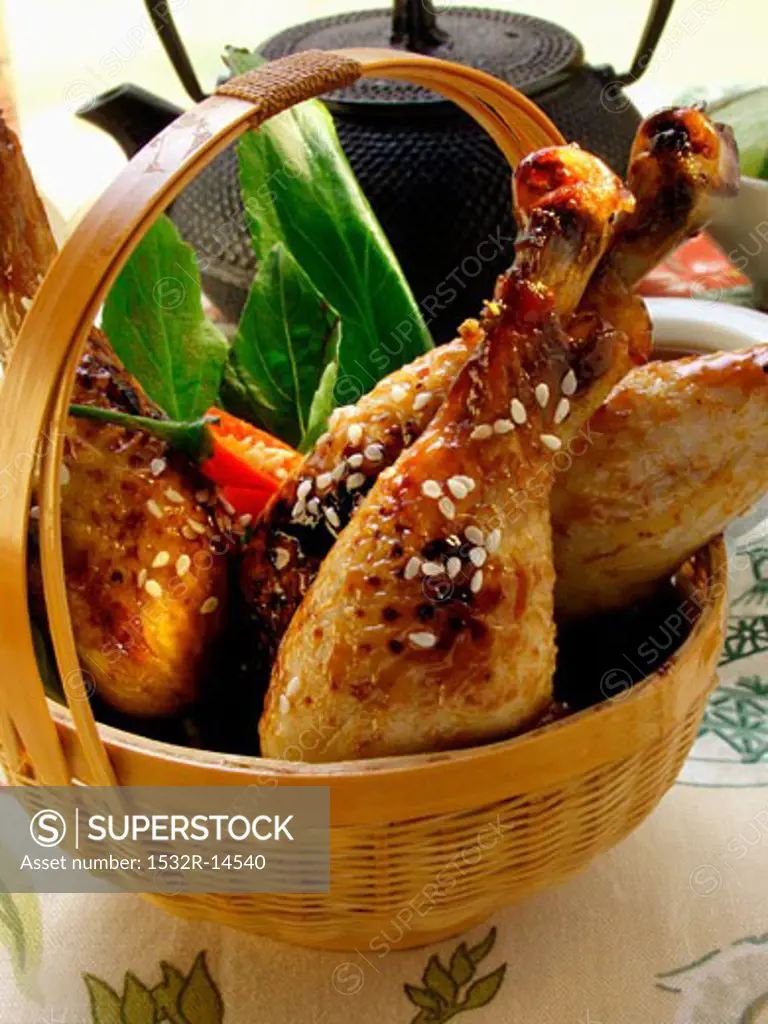 Asian chicken legs with sesame in basket, teapot