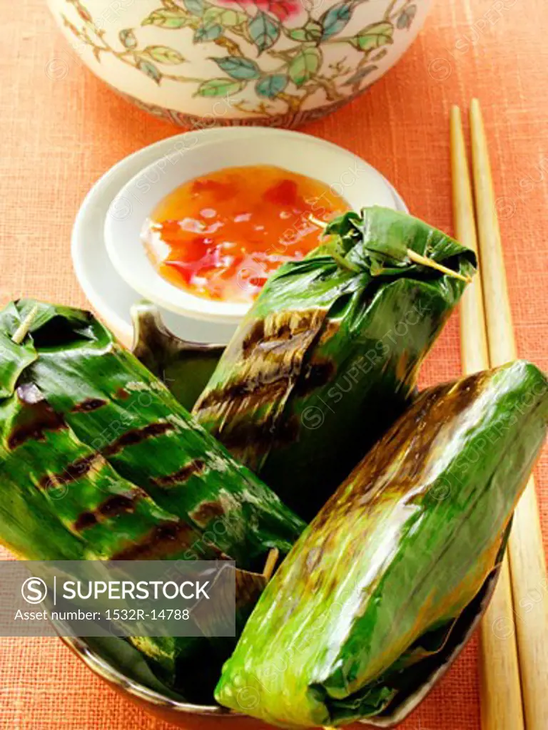 Asian rice parcels in banana leaf with chili sauce