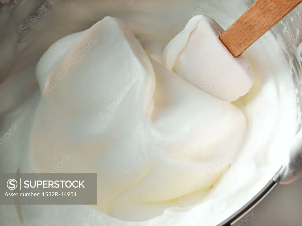 Whipped cream in mixing bowl with spatula