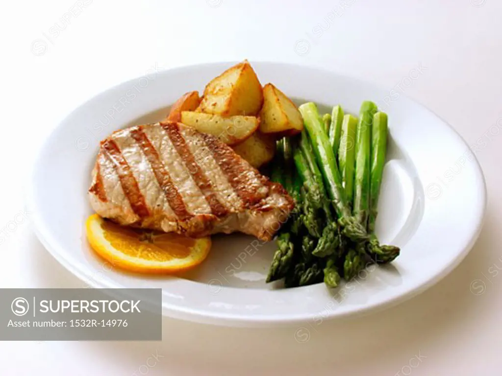 Pork steak with green asparagus, fried potatoes, orange