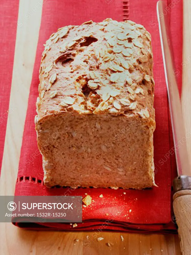 Wholemeal bread with oat flakes on red napkin, knife