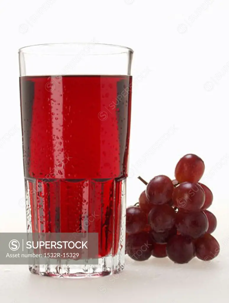Glass of red grape juice with drops of water & red grapes