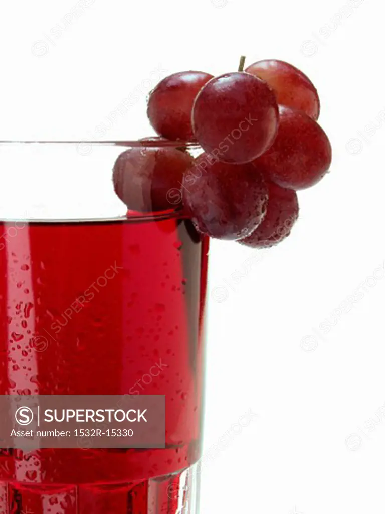 Red grapes on glass of red grape juice (detail)