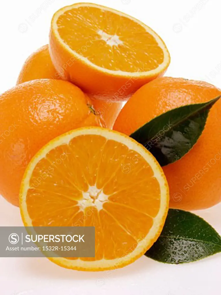 Whole and half oranges with leaves and drops of water