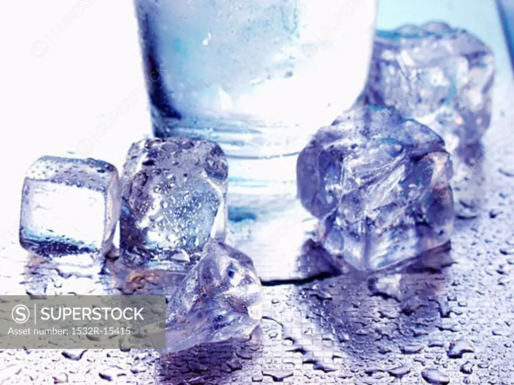 Several ice cubes in front of water glass