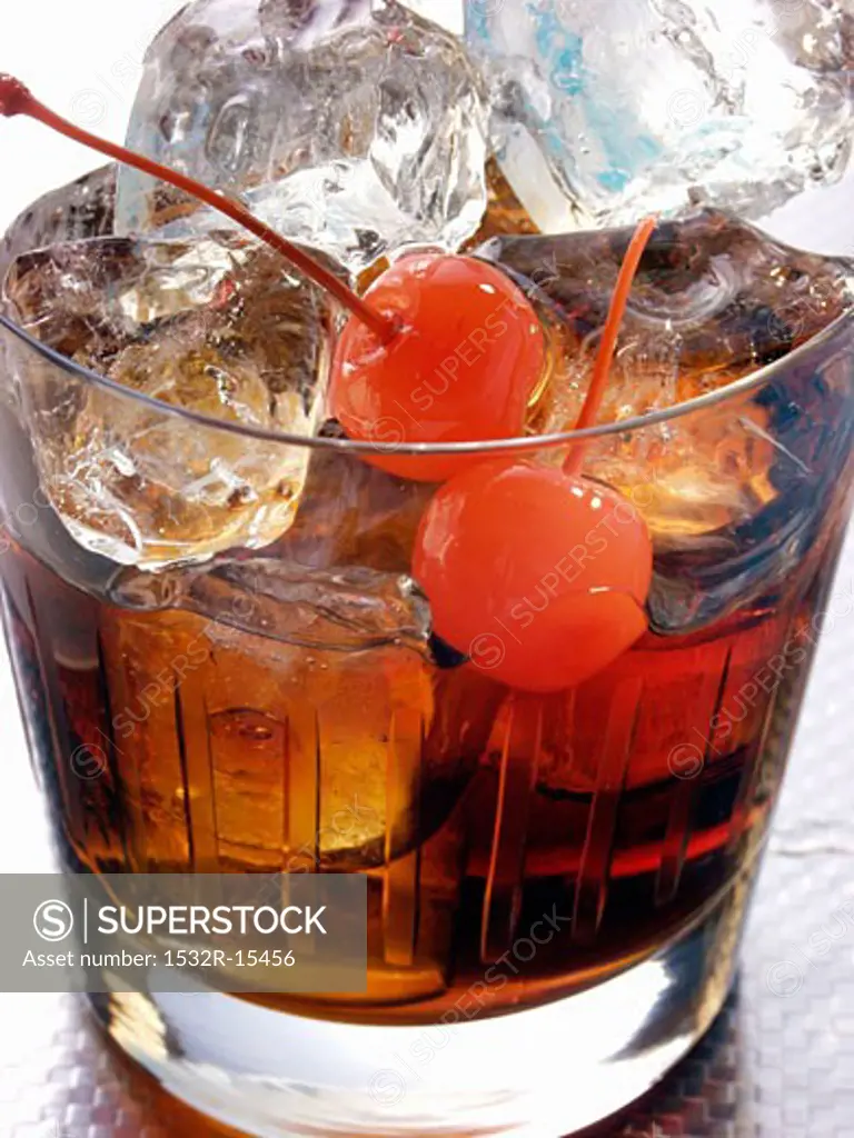 Drink with rum, ice cubes and cocktail cherries