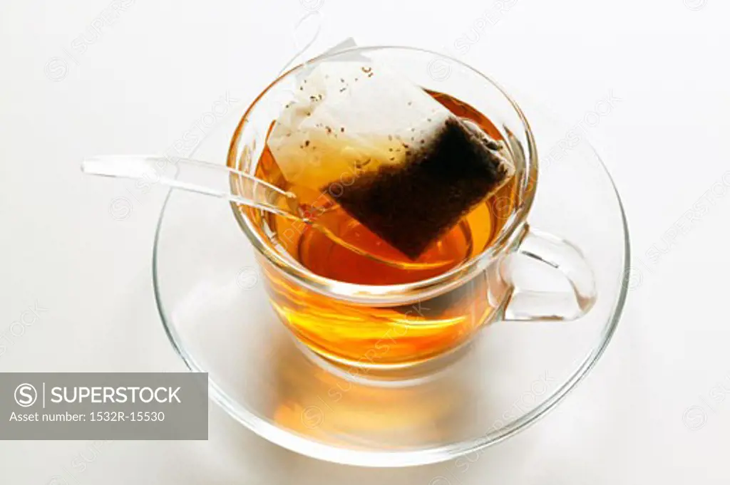Tea in glass cup with tea bag and spoon