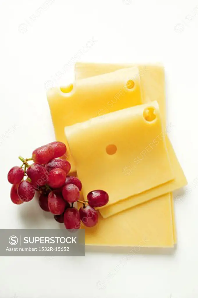 Emmental cheese in slices with red grapes