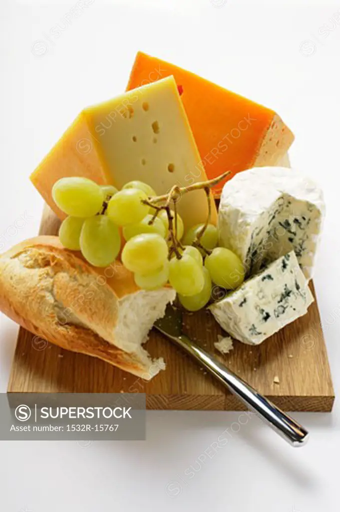 Various types of cheese with grapes and baguette