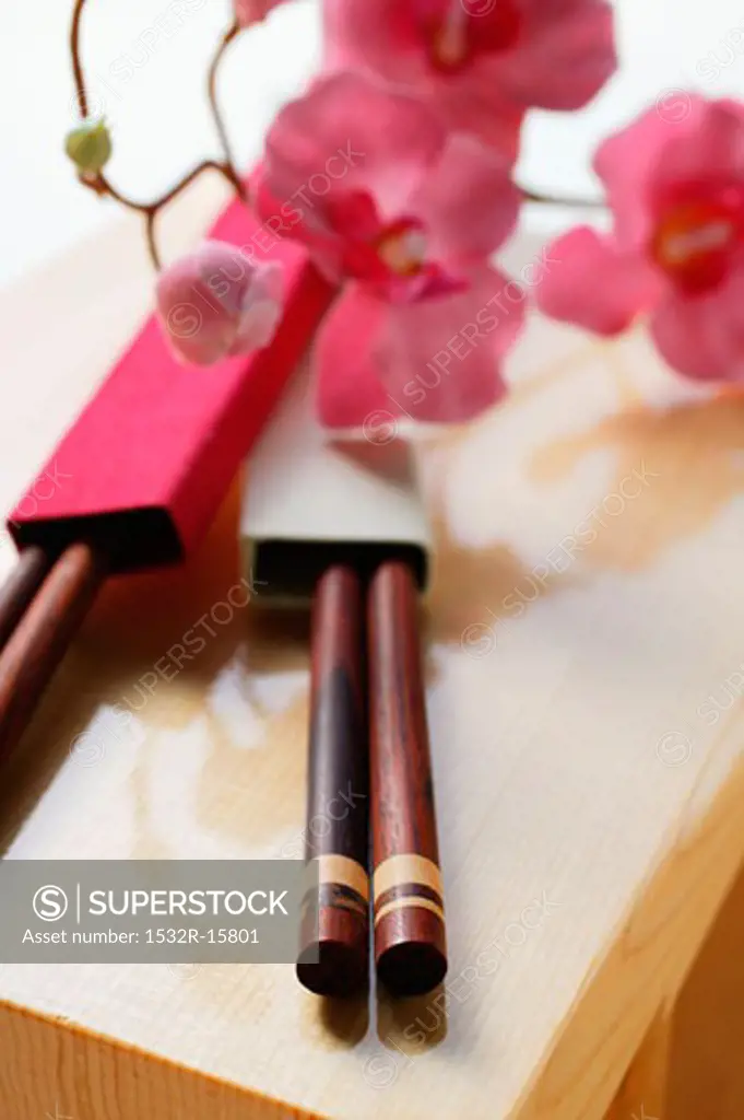 Japanese chopsticks and flowers on wooden board