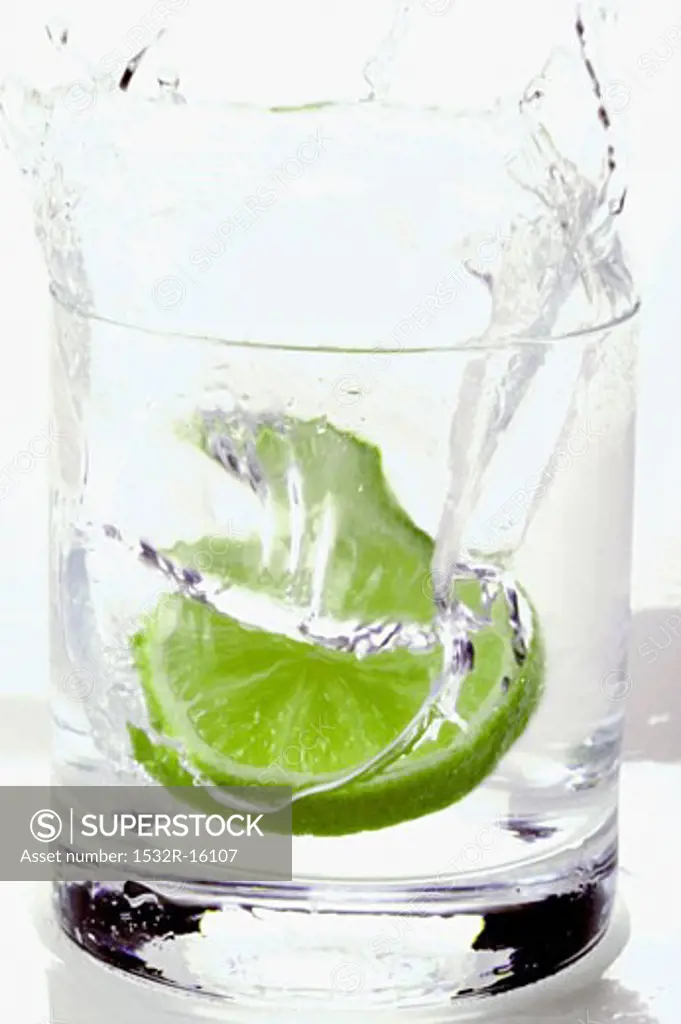 Pouring water into a glass with a slice of lime