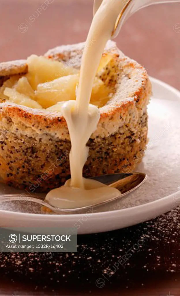 Pouring custard over pineapple and poppy seed soufflé