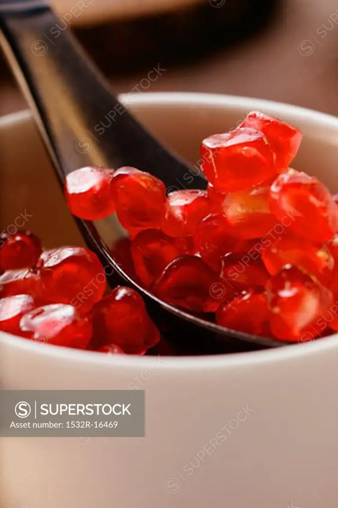 Pomegranate seeds in small bowl with spoon