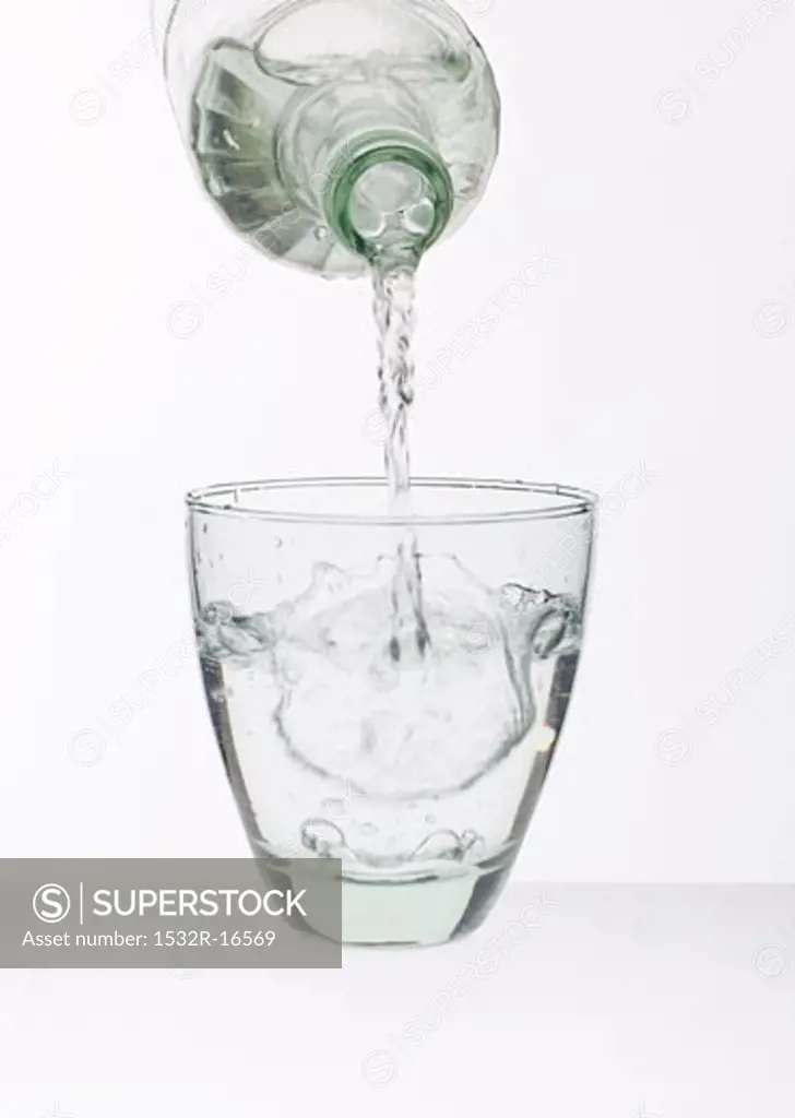 Pouring water out of bottle into glass