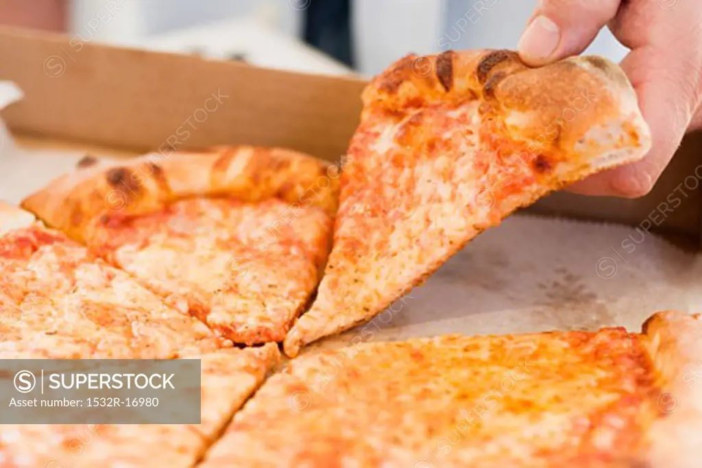 Hand taking piece of Pizza Margherita out of pizza box
