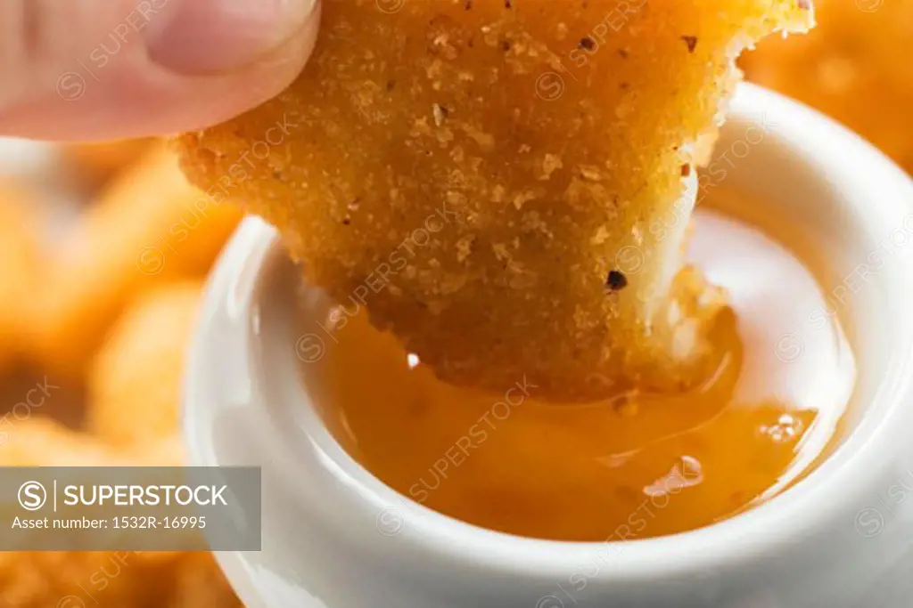 Dipping a chicken nugget in apricot sauce
