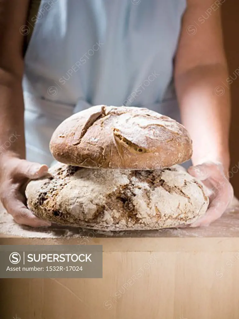 Woman holding two loaves of Bauernbrot (German farmhouse bread)