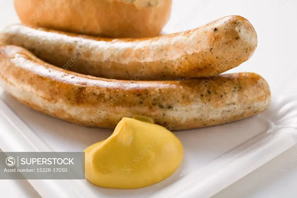 Two sausages with mustard and bread roll