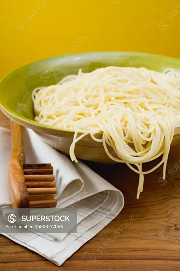 A dish of cooked spaghetti with spaghetti server
