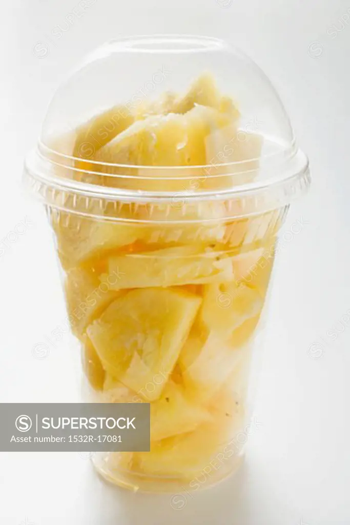 Pineapple chunks in a plastic cup with a lid