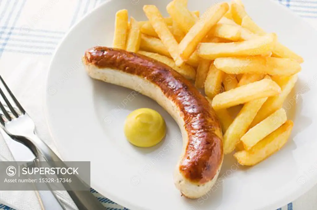 Sausage with chips and mustard on plate