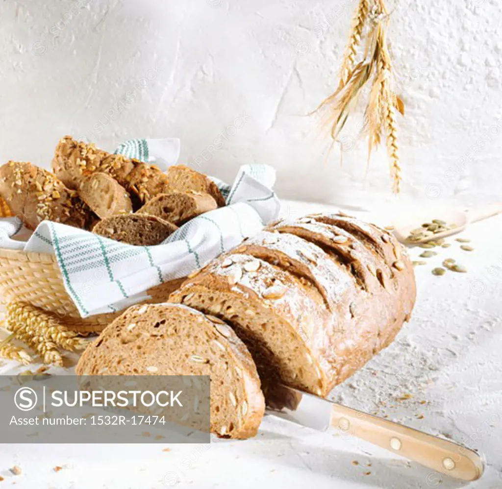 Sunflower seed bread, a slice cut; bread rolls in bread basket