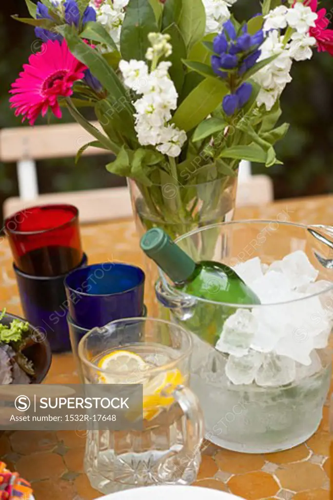 Table with white wine, lemon water, flowers, glasses (outside)