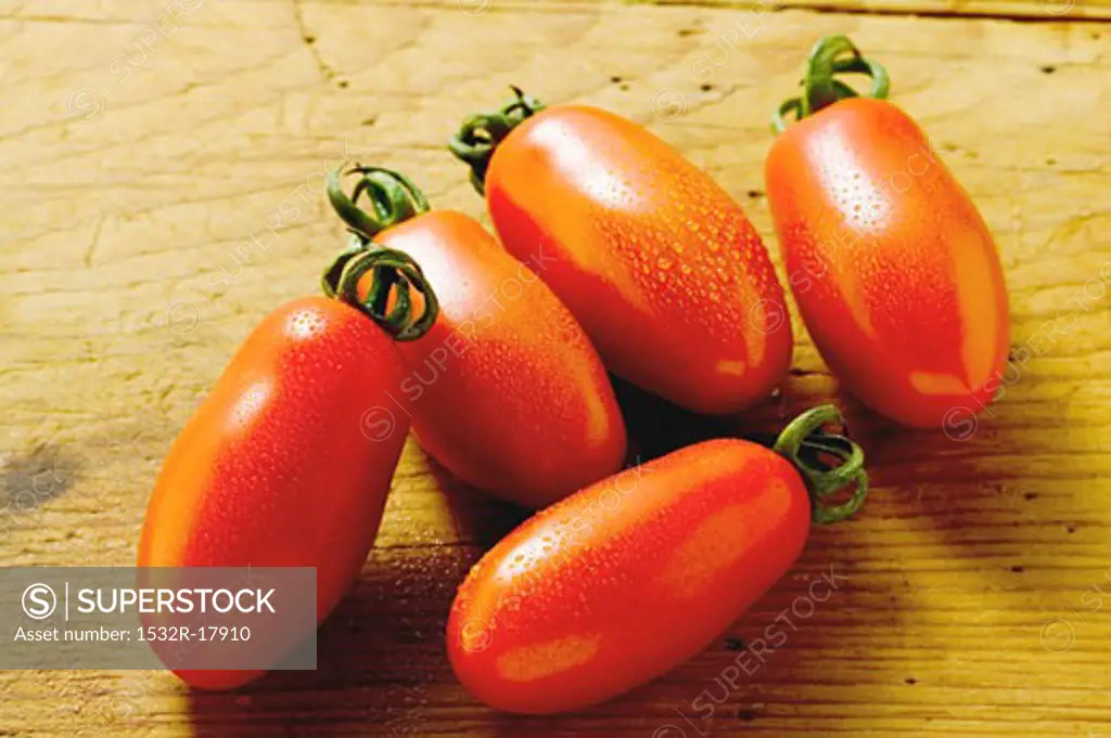 Five 'date' tomatoes on wooden background