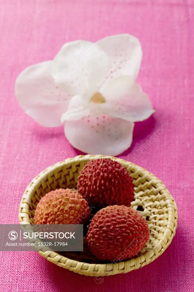 Lychees in basket in front of orchid
