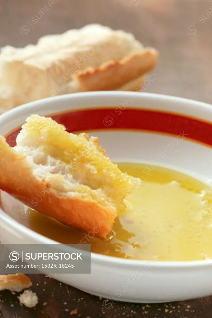 Piece of white bread in a small bowl of olive oil
