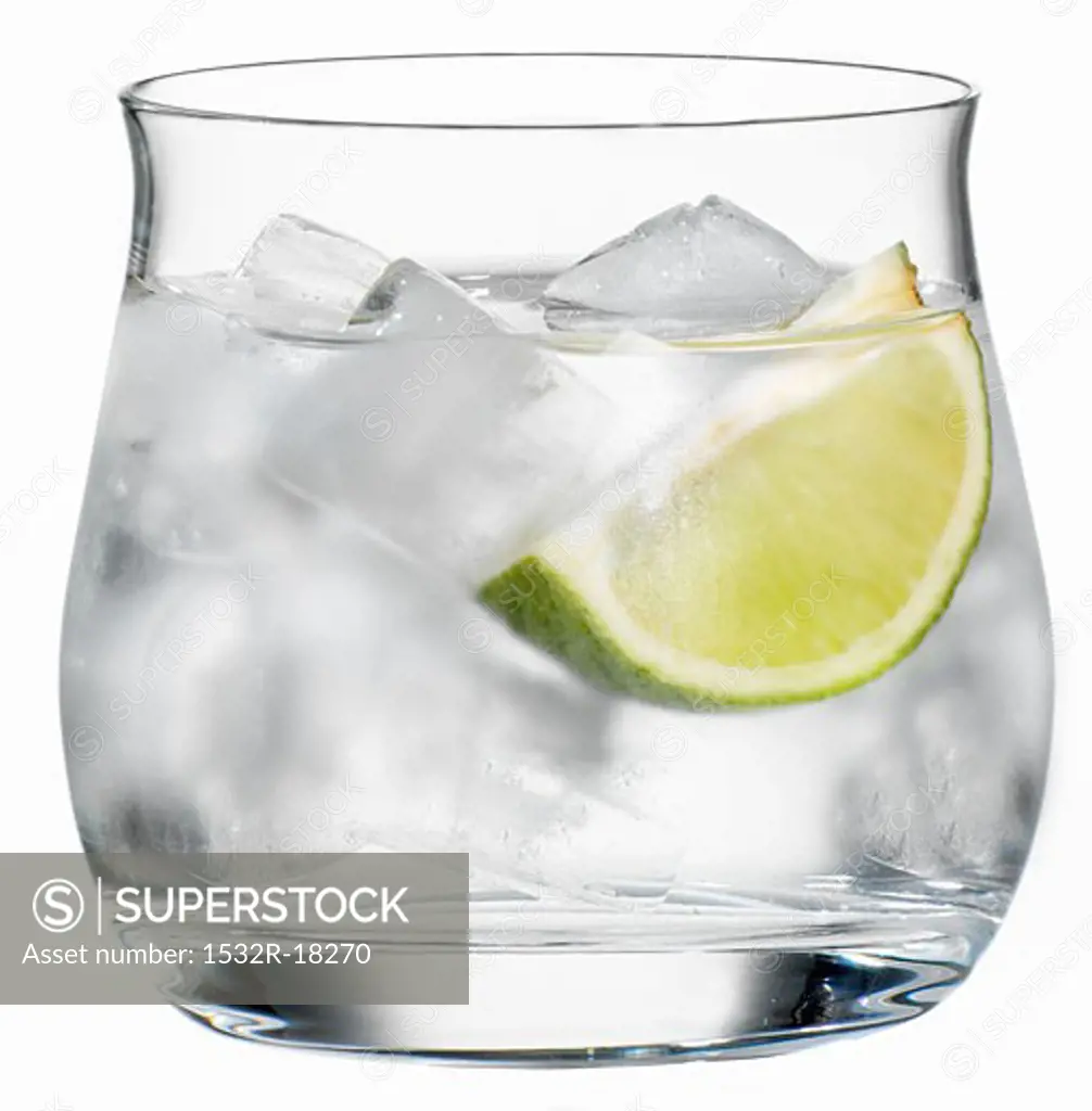 A glass of water with ice cube and a wedge of lime