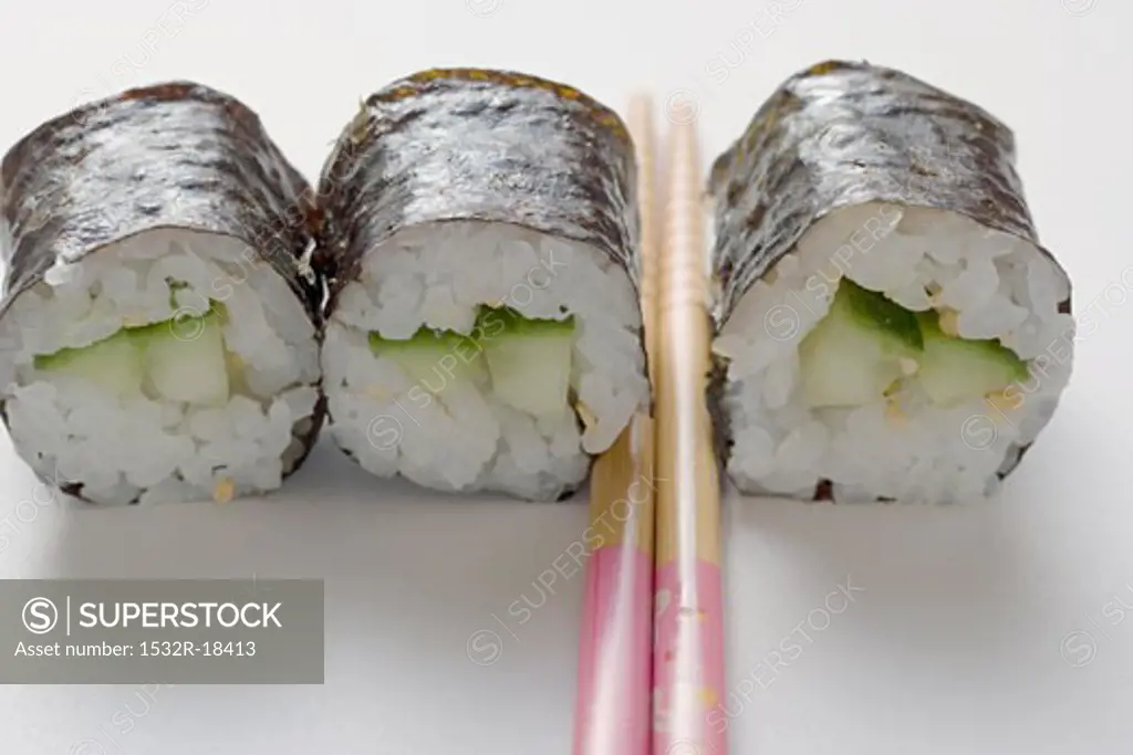 Three maki sushi with cucumber and chopsticks