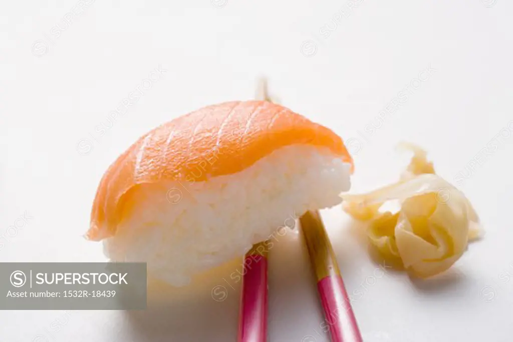 Nigiri sushi with salmon on chopsticks and preserved ginger