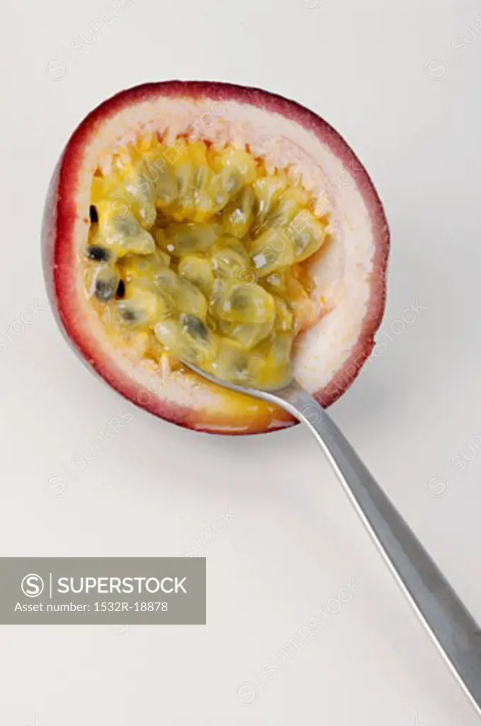 Half of a passion fruit being hollowed out