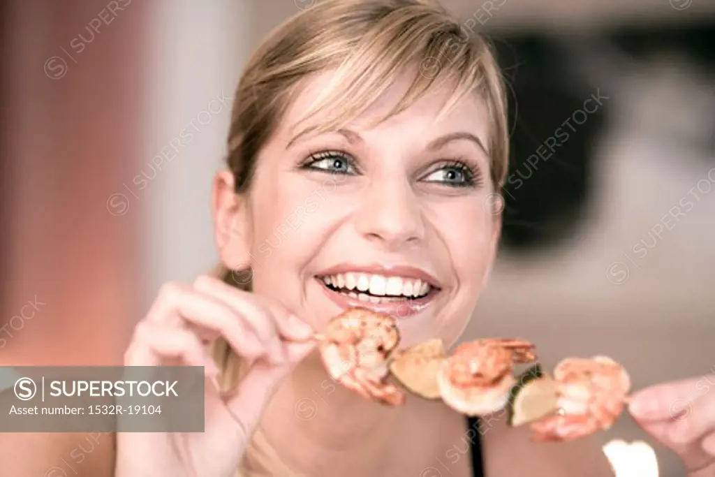 Young woman with shrimp kebab in her hand