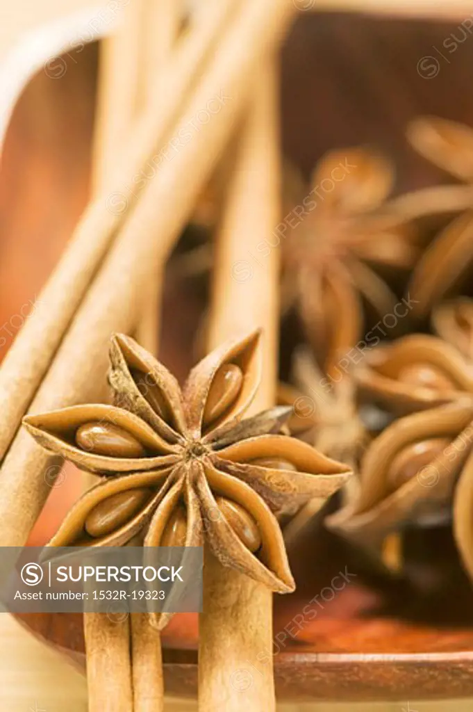 Star anise and cinnamon sticks in wooden bowl