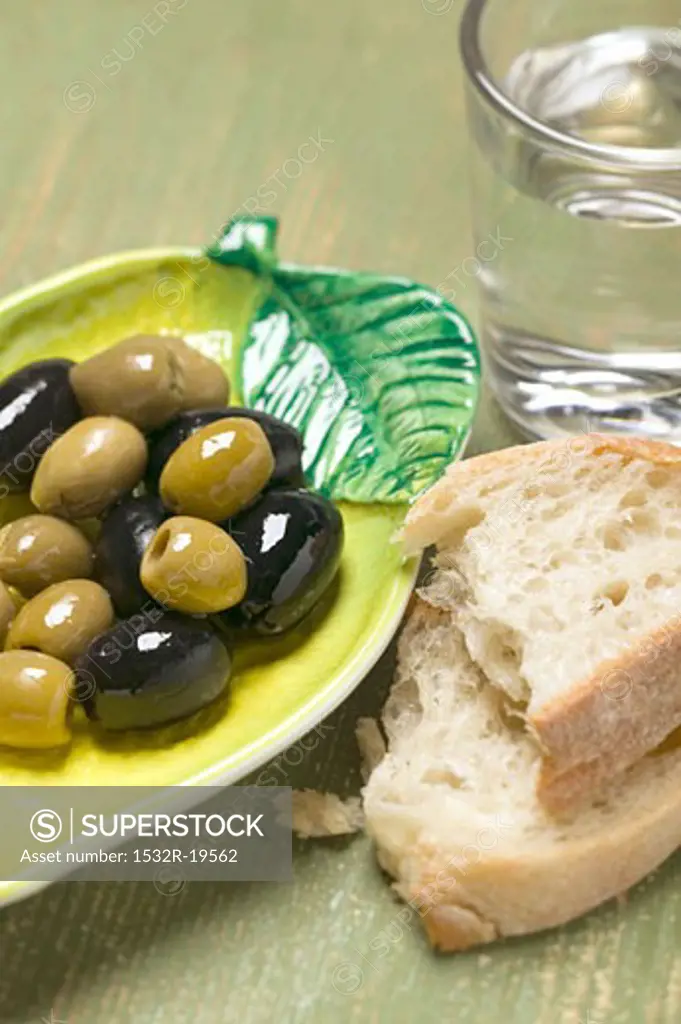 Olives, white bread and glass of water