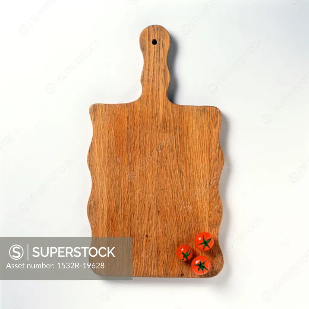 A Wooden Cutting Board with Three Cherry Tomatoes