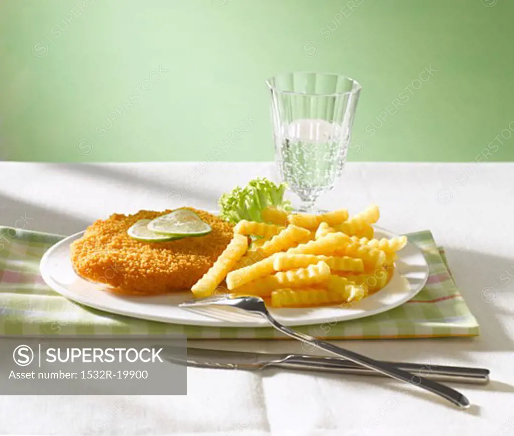 Wiener Schnitzel with lime slices, chips & glass of water