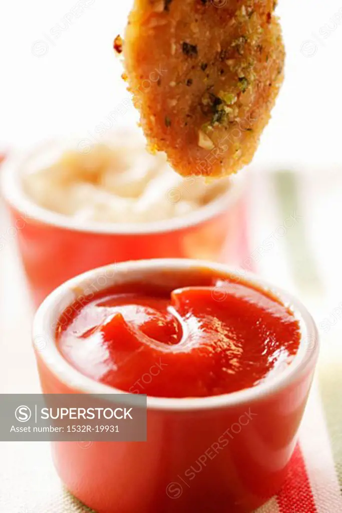 Dipping chicken nugget into ketchup