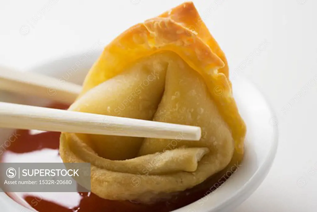 Dipping a deep-fried wonton in sweet and sour sauce