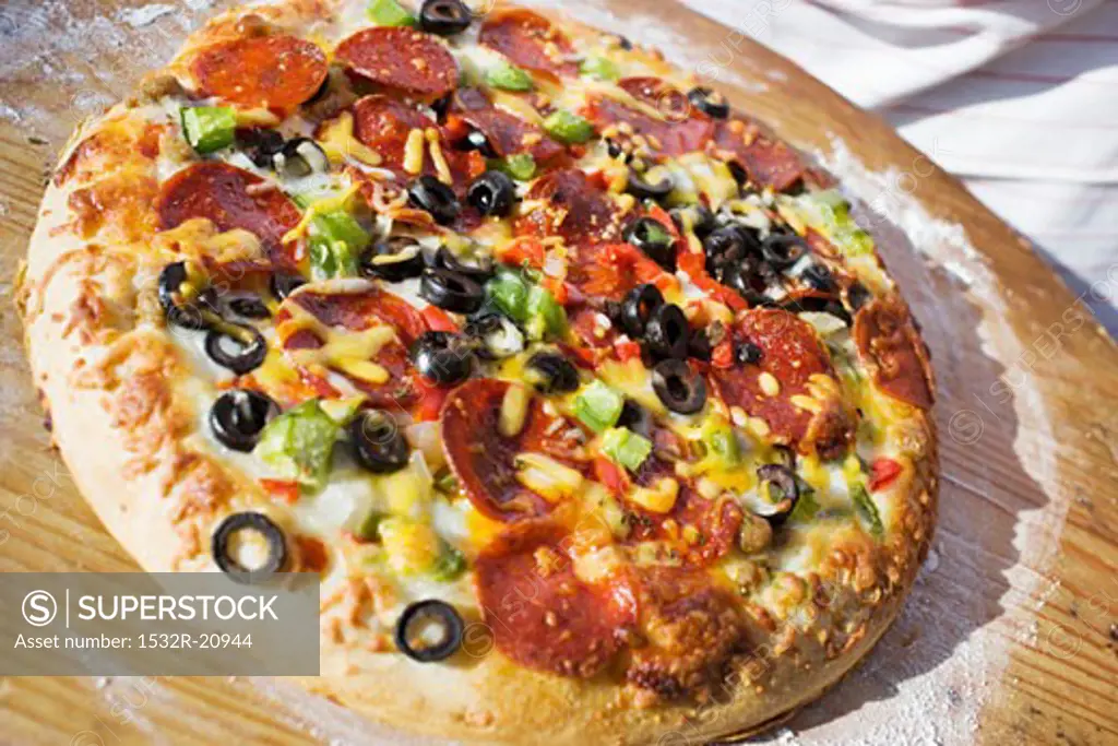 Pepperoni pizza with peppers and olives on wooden plate