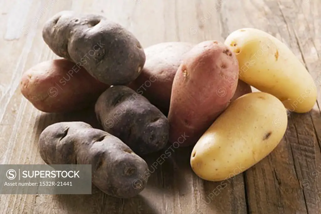 Various types of potato on wooden background