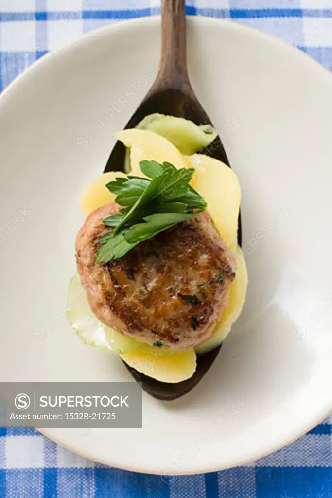 Burger with potato and cucumber salad on spoon