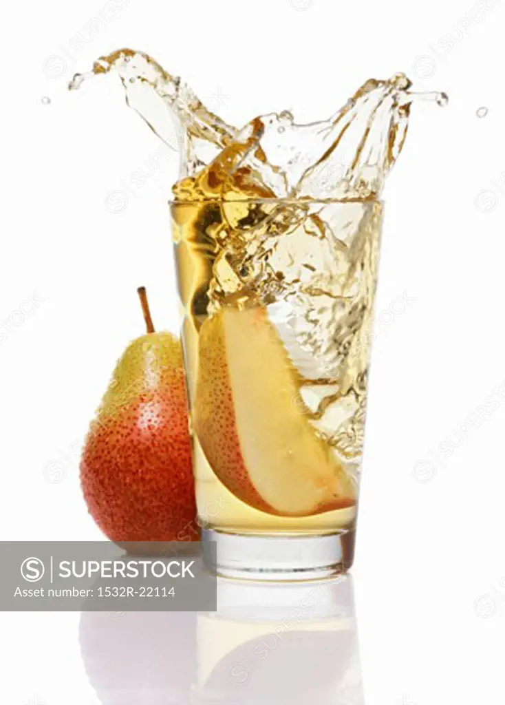 Wedge of pear falling into a glass of pear juice