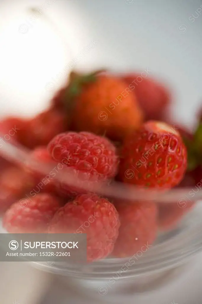 Fresh raspberries and strawberries in a glass bowl
