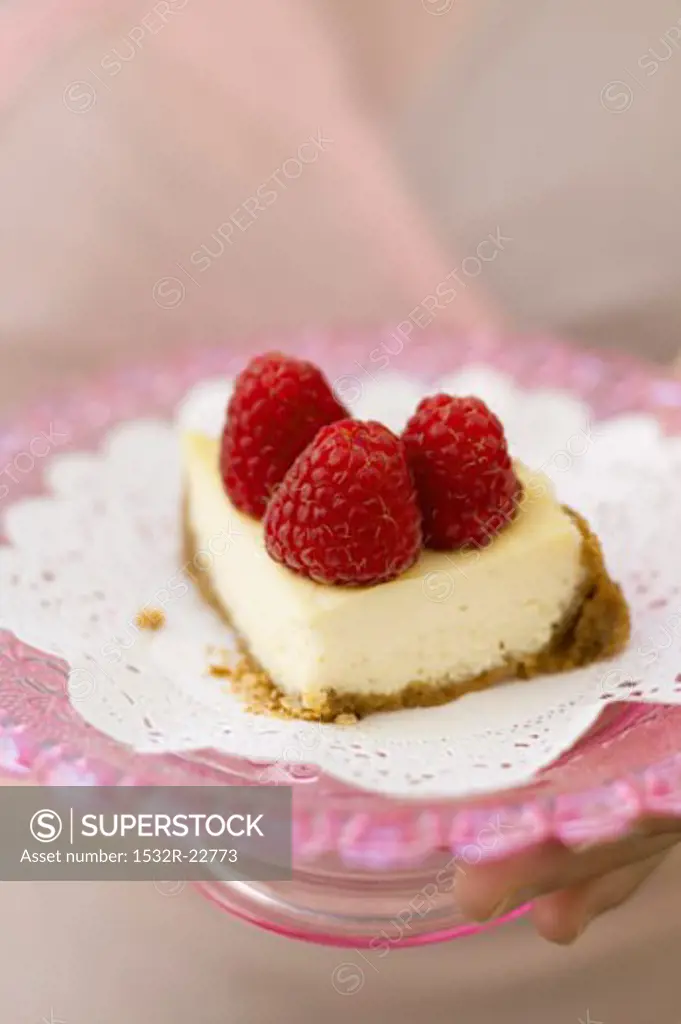 A piece of mini-cheesecake with raspberries