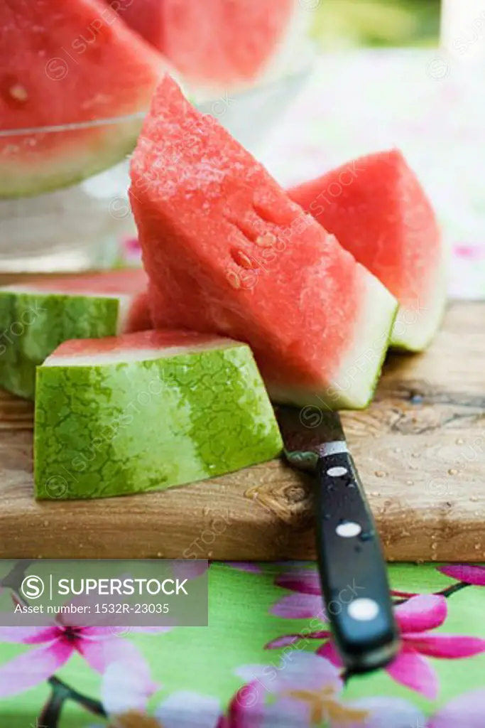 Watermelon, cut into pieces, on a wooden board
