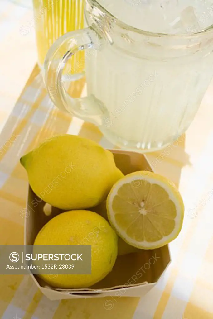 A jug of lemonade and fresh lemons